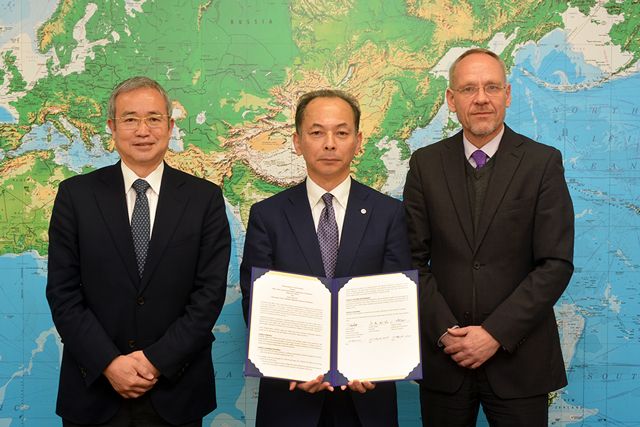 協定書を手にする永尾学長(中央)と星野事務局長(左)、ヘベカー駐日代表